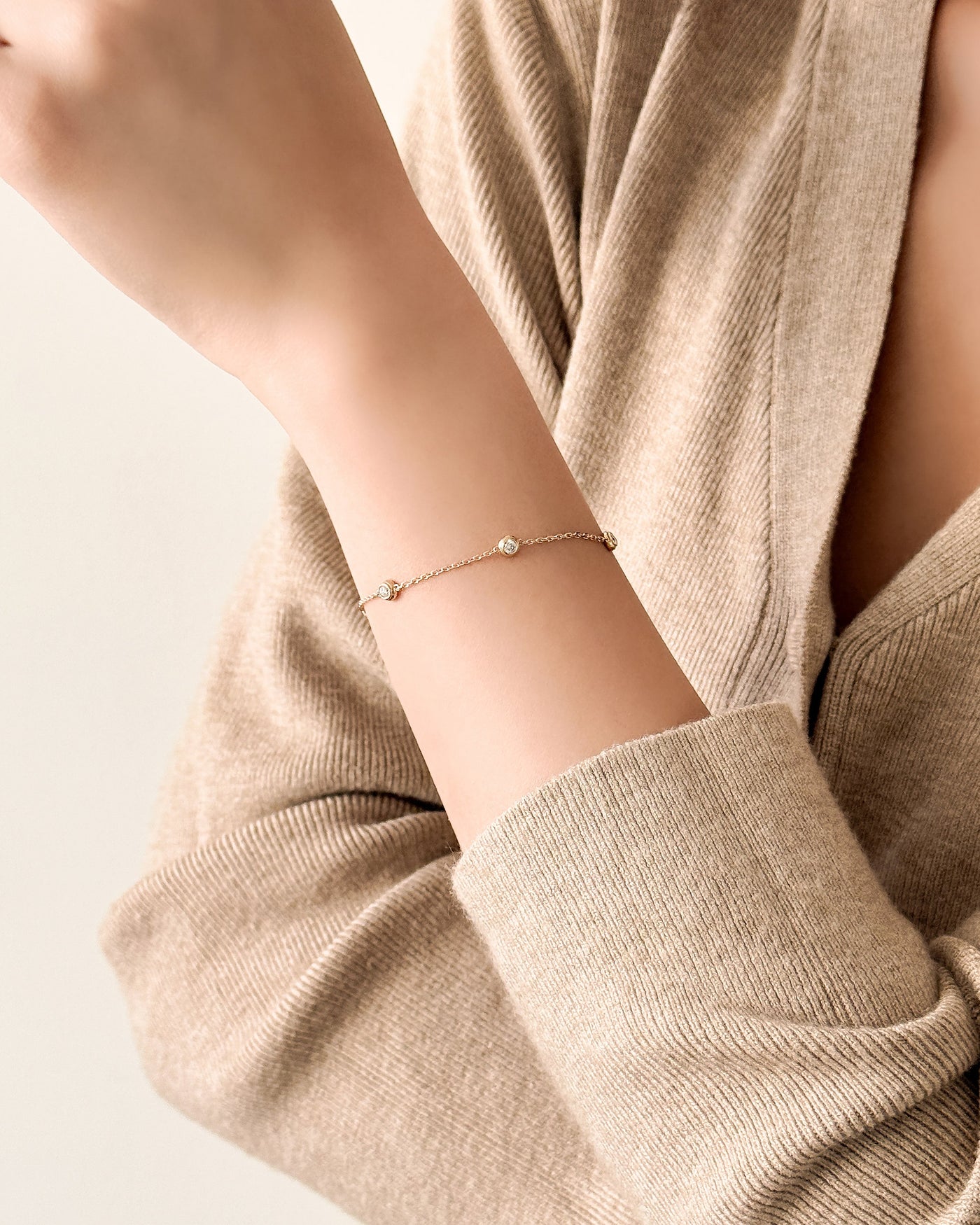 Person wearing a delicate bracelet on a plain background