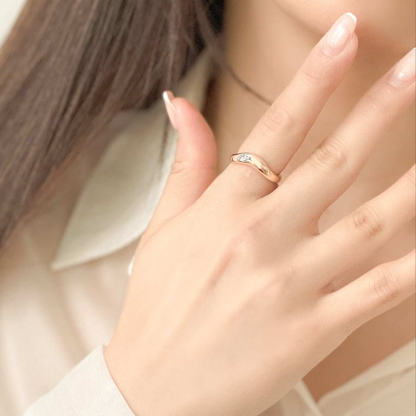 Close-up of a hand wearing a gold ring with a soft focus background