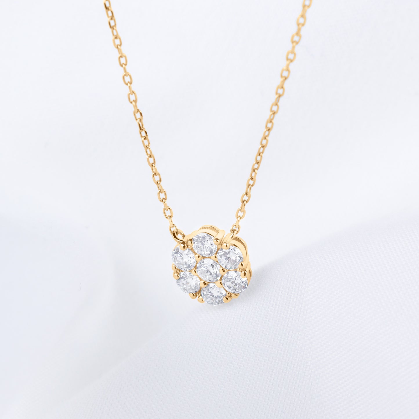 Gold necklace with a flower-shaped diamond pendant on a light gray background