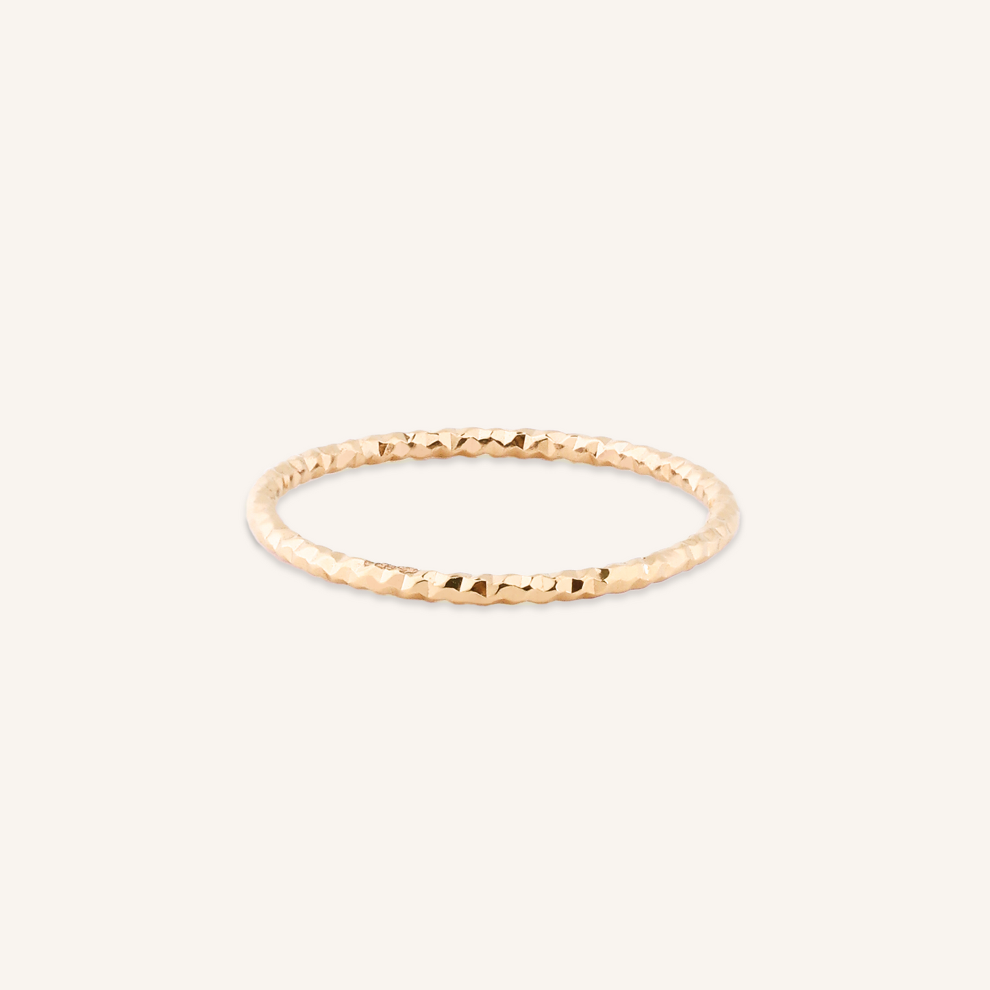 Gold ring with a textured band on a white background
