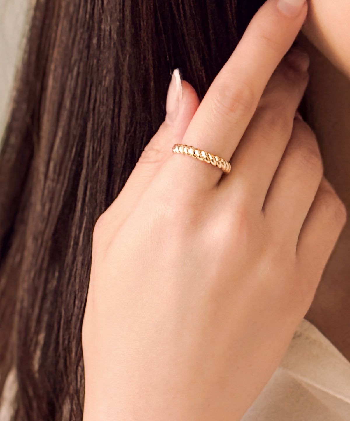 Brioche Ring worn on the index finger, hand at the cheek