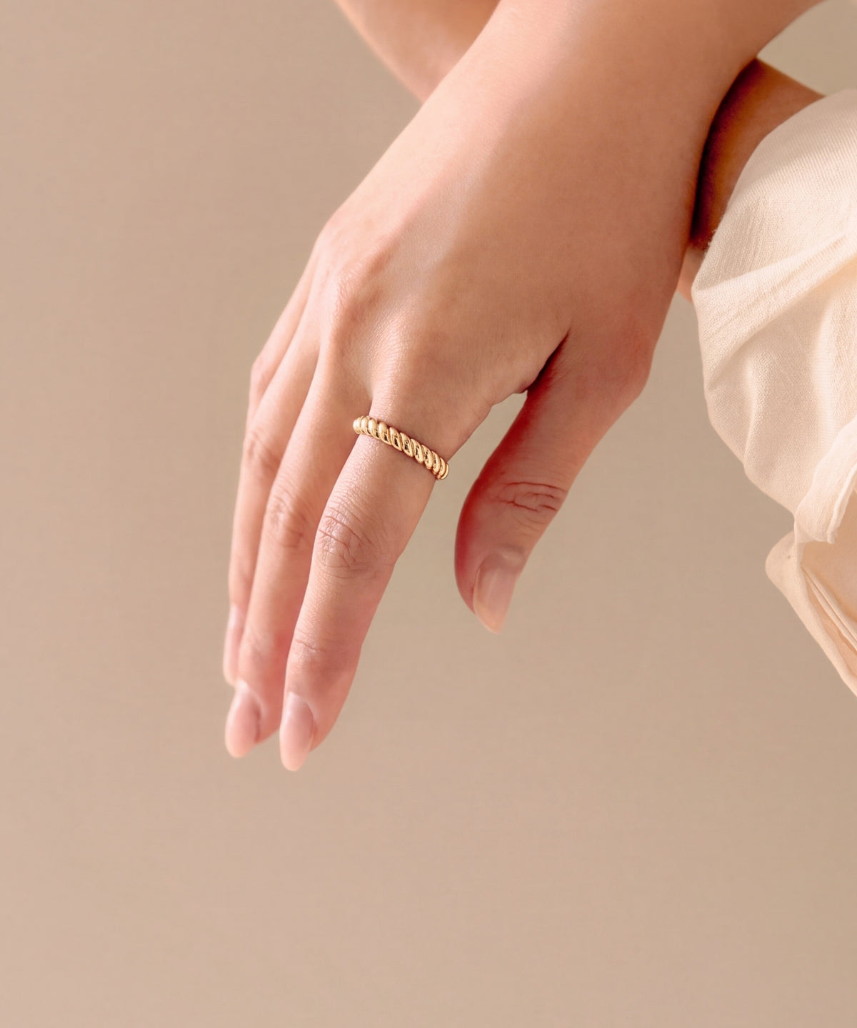 Brioche Ring on the middle finger, hand resting on a sleeve