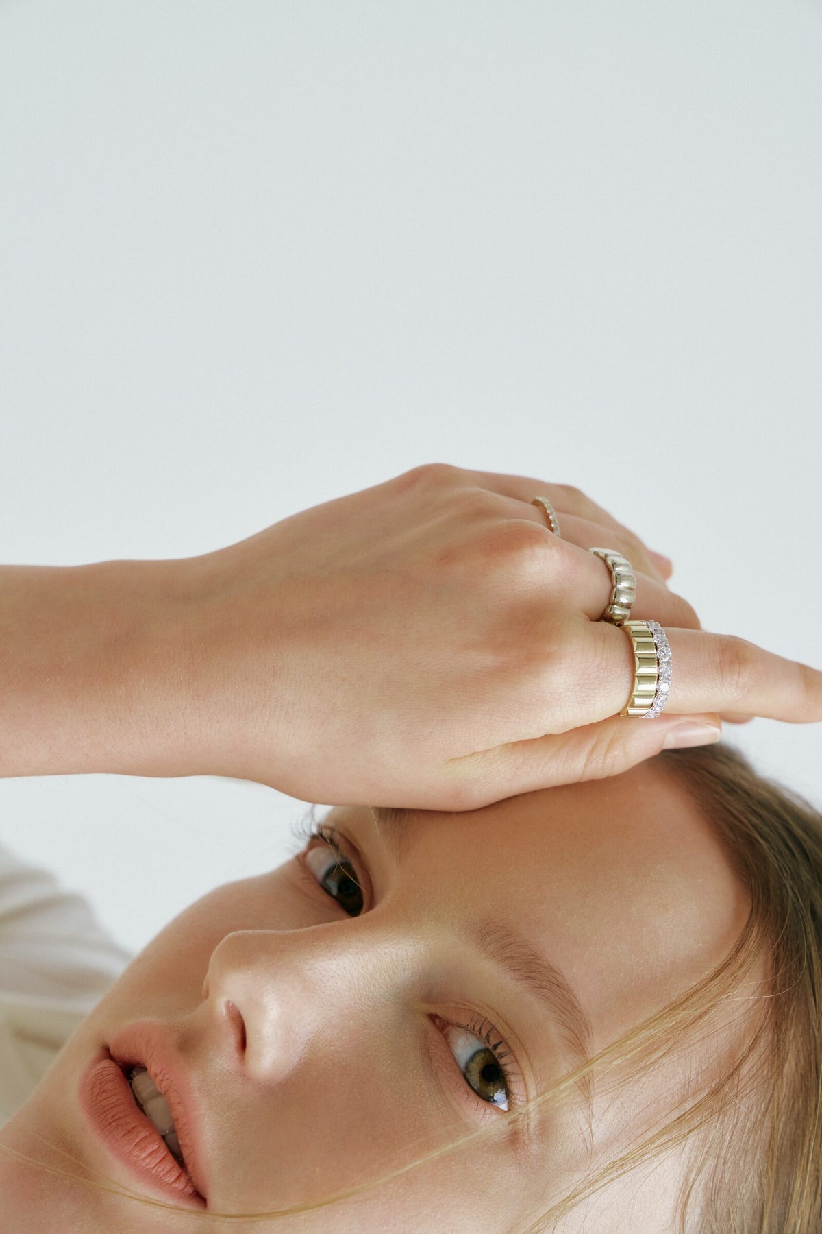 A hand across her brow, a Pillow Ring above a wide fluted band and a stone band.