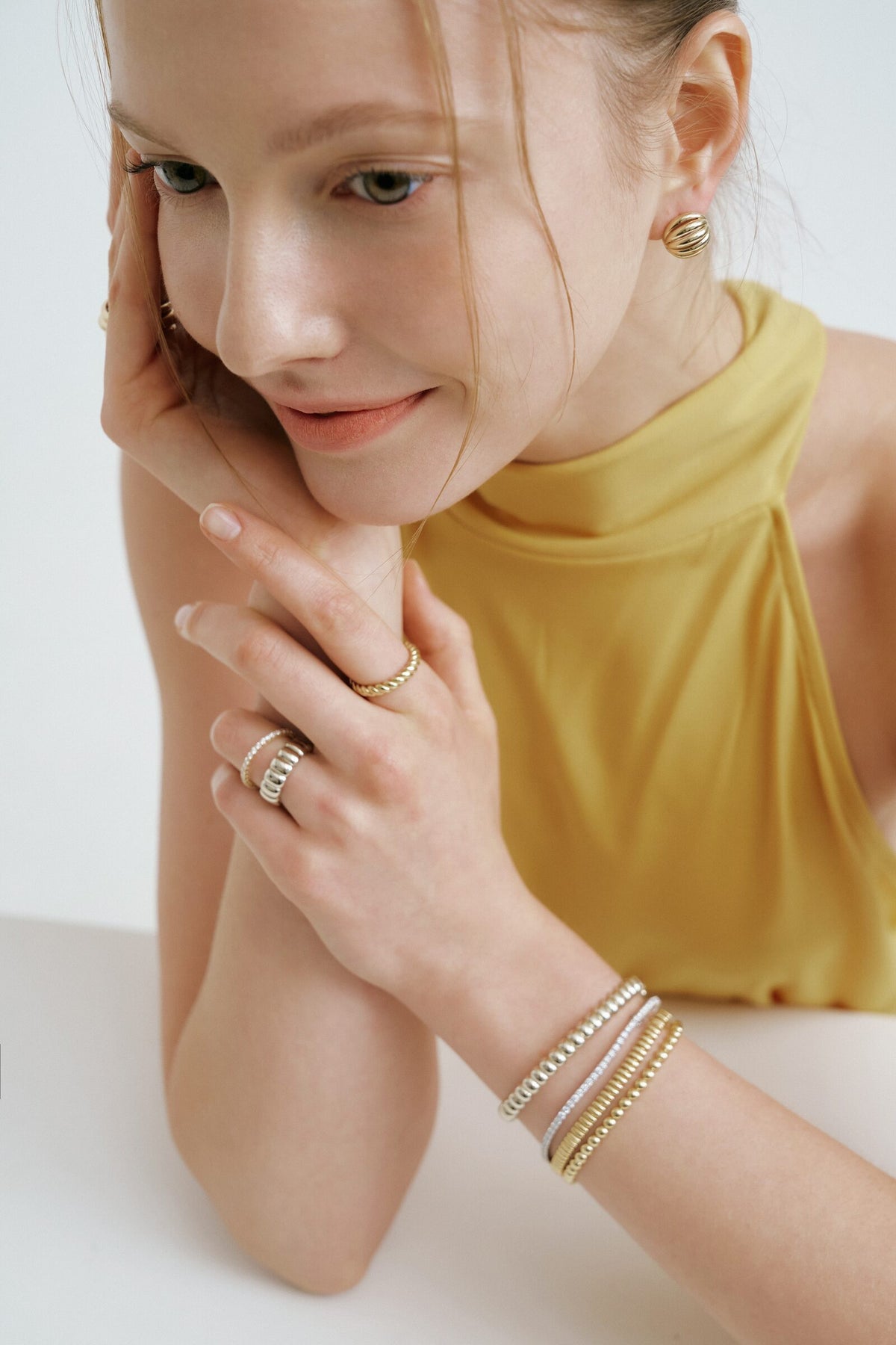 Sequence, frame 1 of 4: leaning on her hands, a stack of bracelets at the wrist.