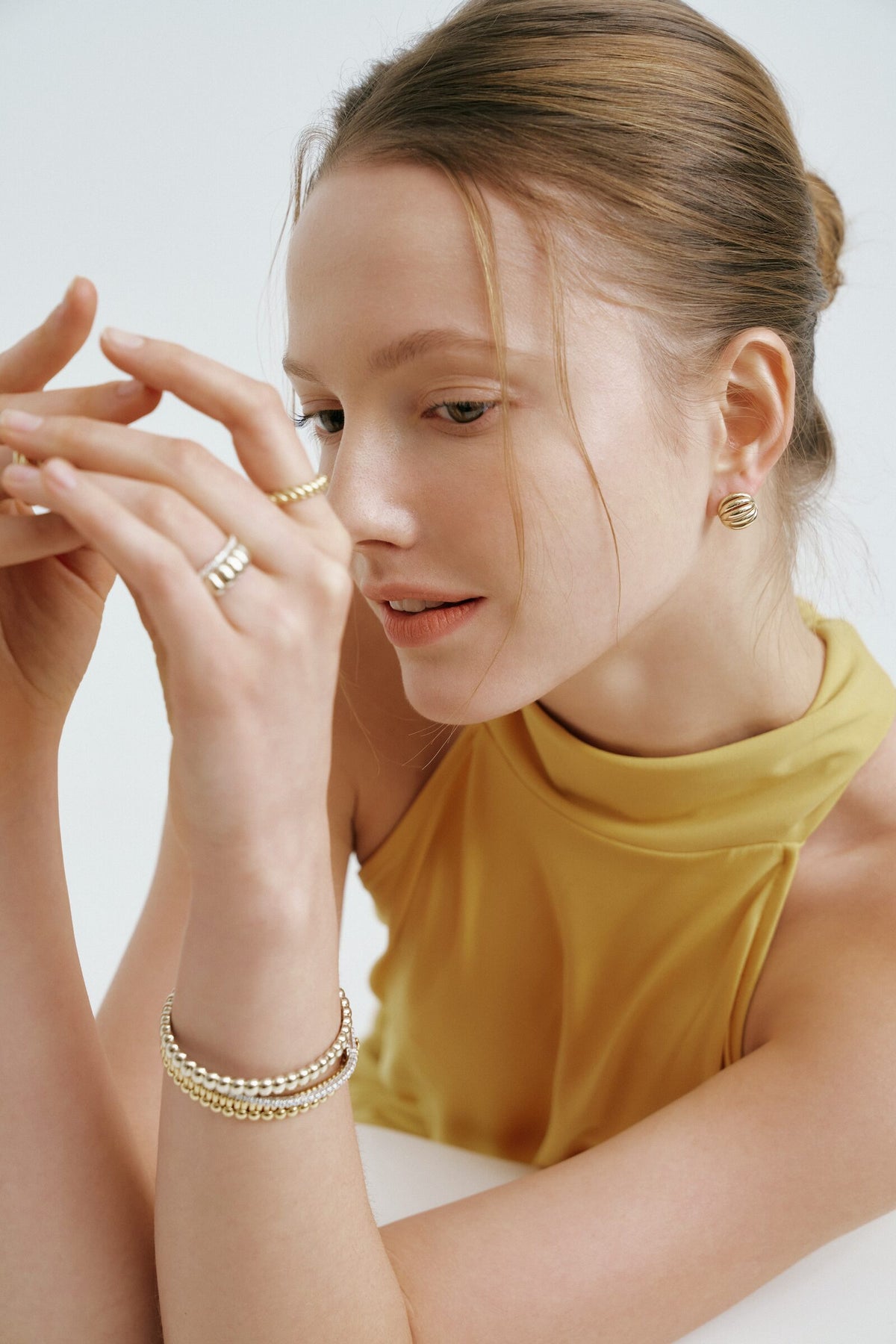 Frame 4 of 4: fingers at her lips, still laughing, rings and bracelets catching the light.