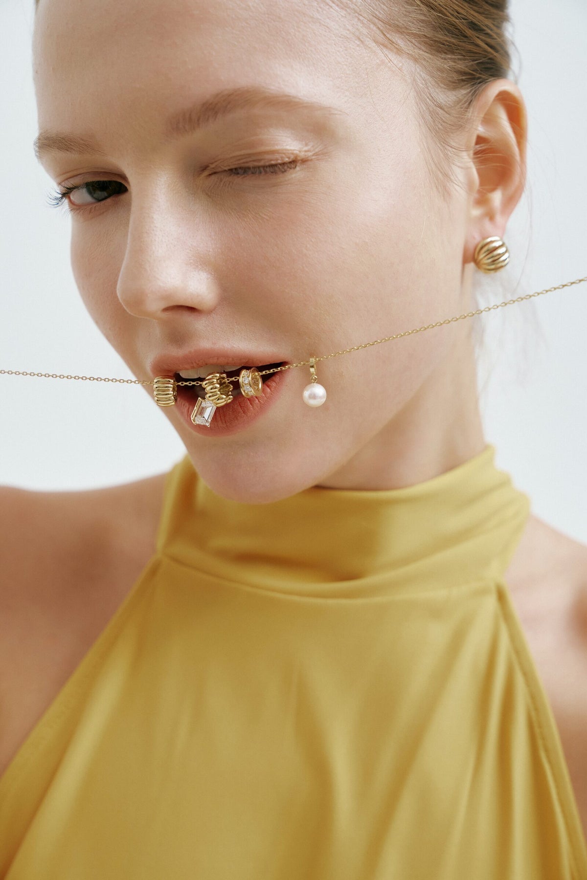 A wink, a gold charm necklace held between her teeth.