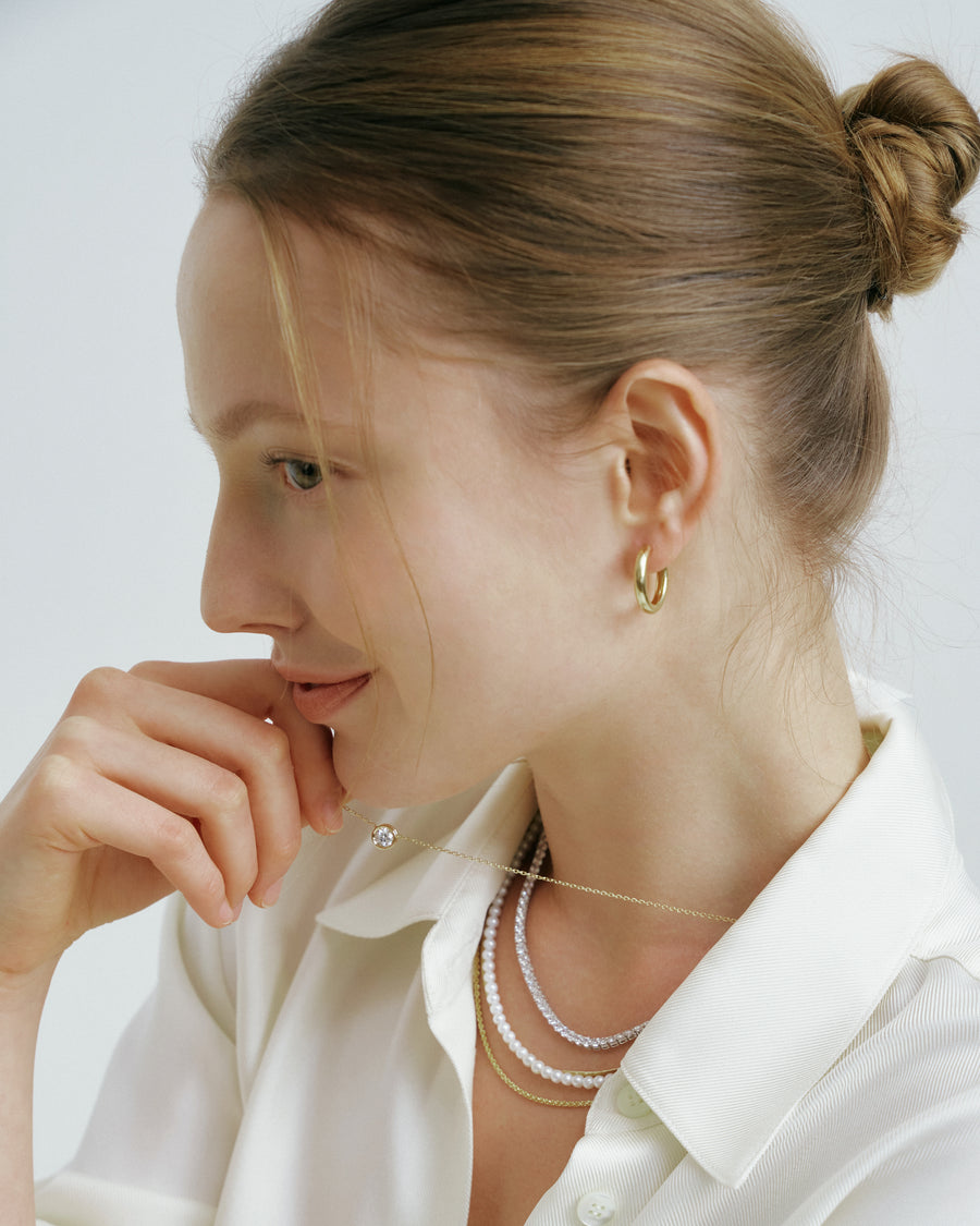 Model in a white shirt wearing gold hoop earrings