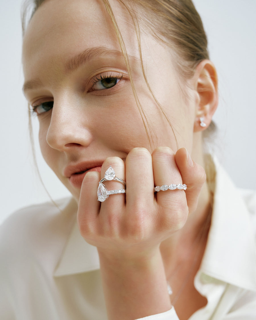 Model resting her chin on a hand wearing diamond rings