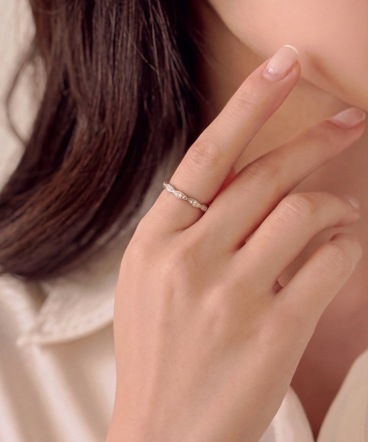 Milgrain marquise eternity band worn on the index finger, hand raised to the chin