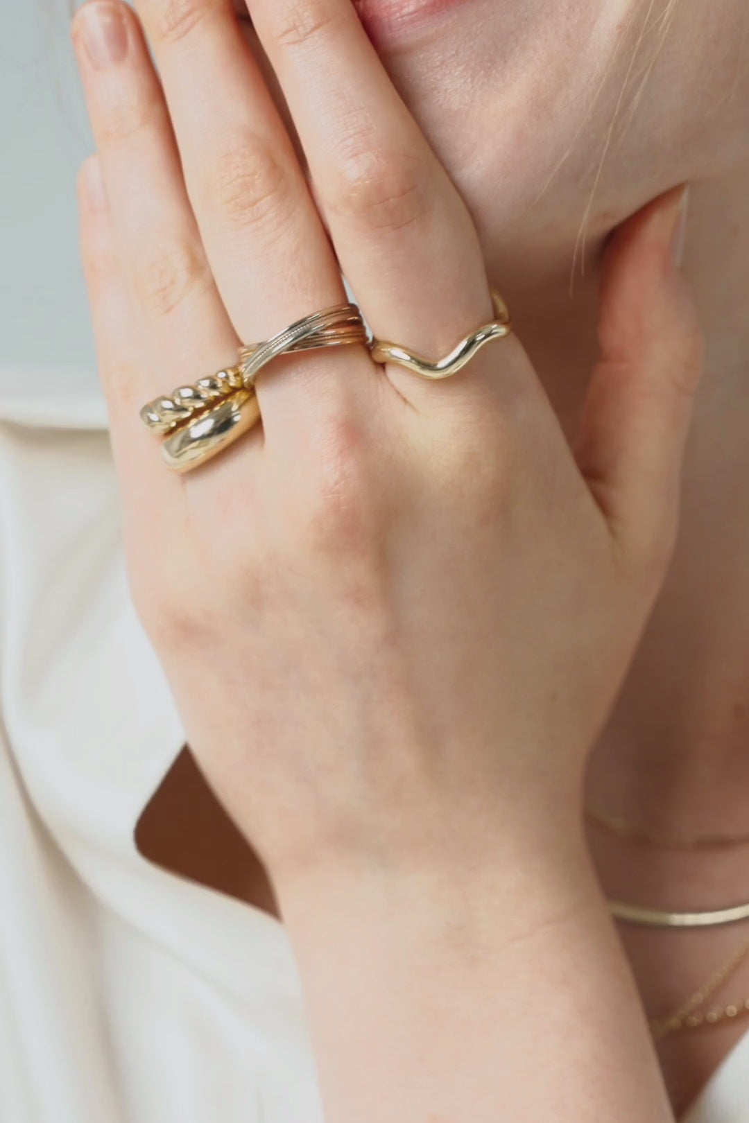 Gold rings over a smile, pearl strands with fine gold chains, and hands laced with stacked rings