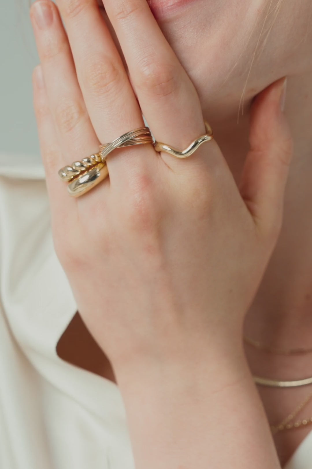 Gold rings over a smile, pearl strands with fine gold chains, and hands laced with stacked rings