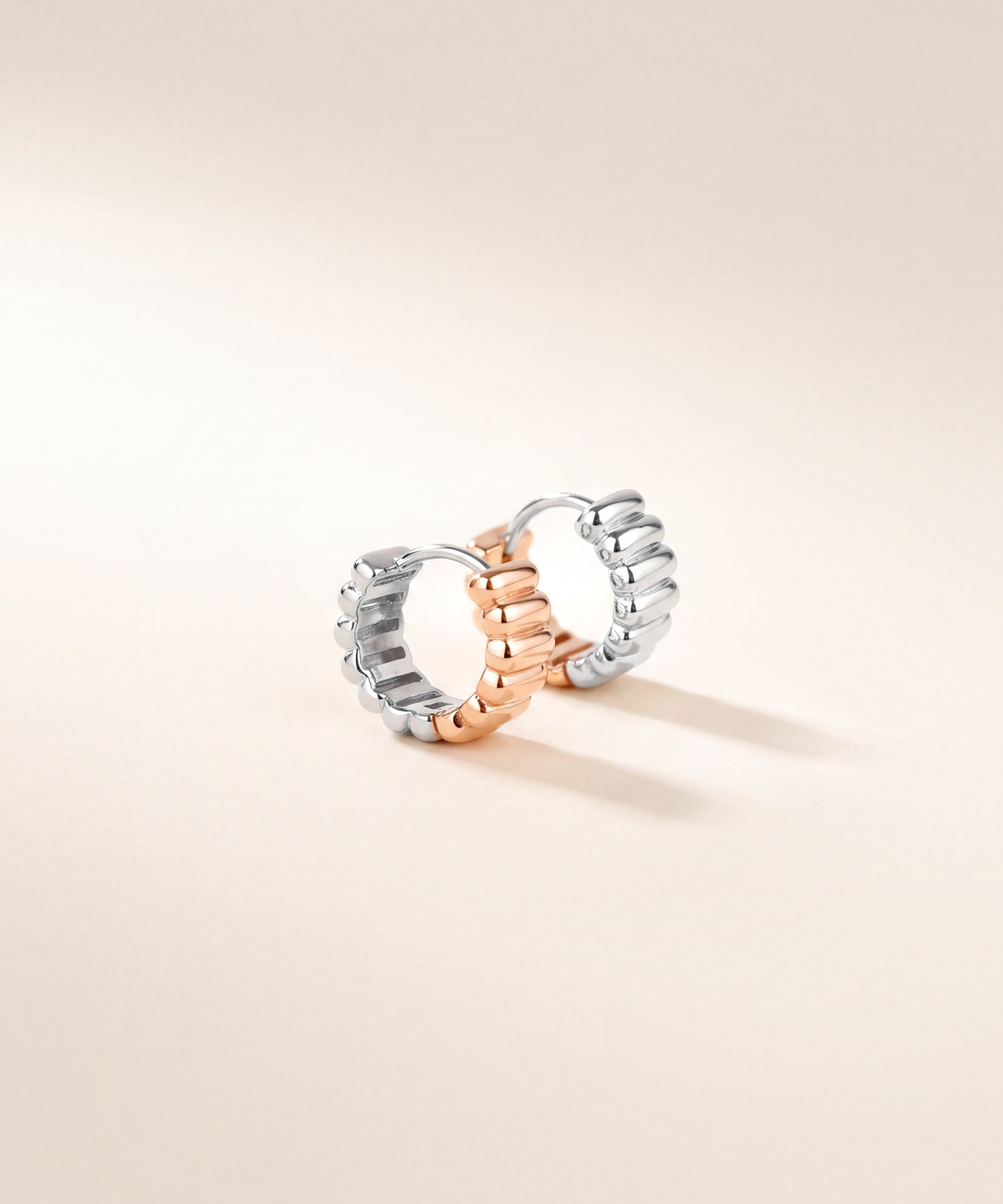 Two-tone ribbed huggie hoop pair, white gold with rose gold, studio shot